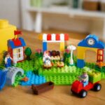 Kolorowy park z klocków LEGO z placem zabaw, straganem i budynkami na zielonej podstawce
