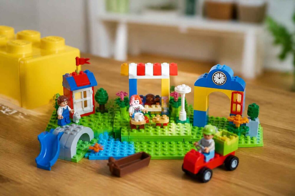 Kolorowy park z klocków LEGO z placem zabaw, straganem i budynkami na zielonej podstawce